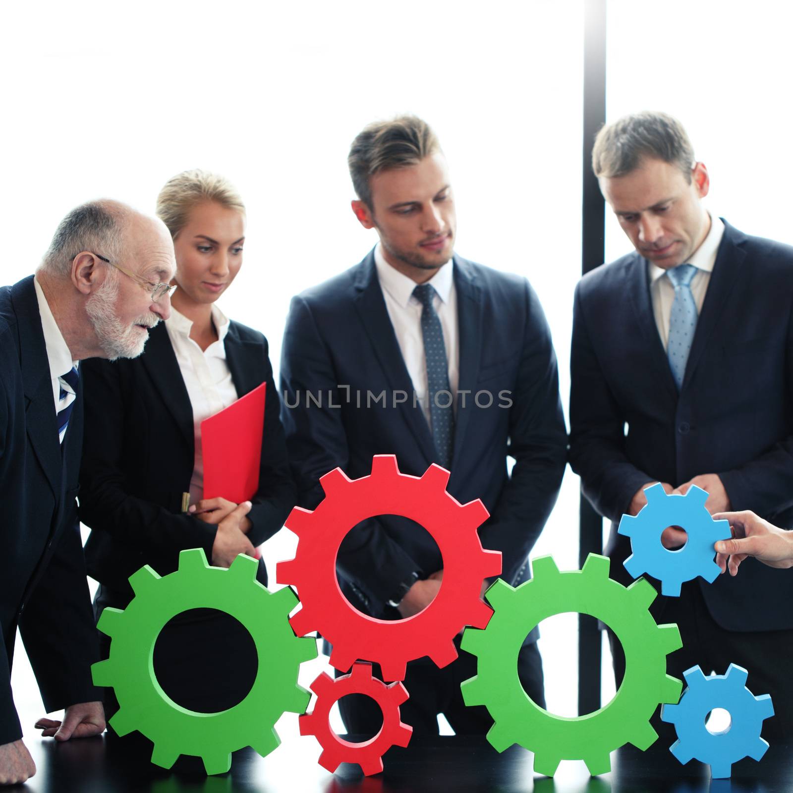 Business people assembling cogwheels, teamwork concept