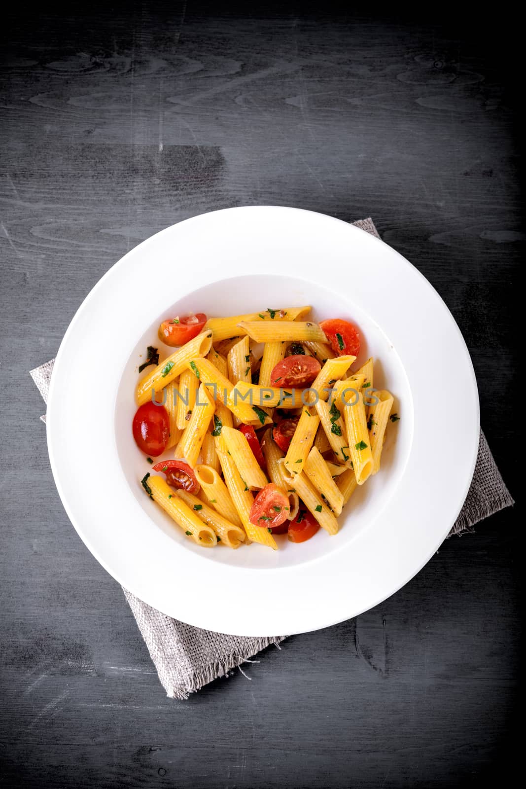 Penne with anchovy and tomato on a wooden surface
