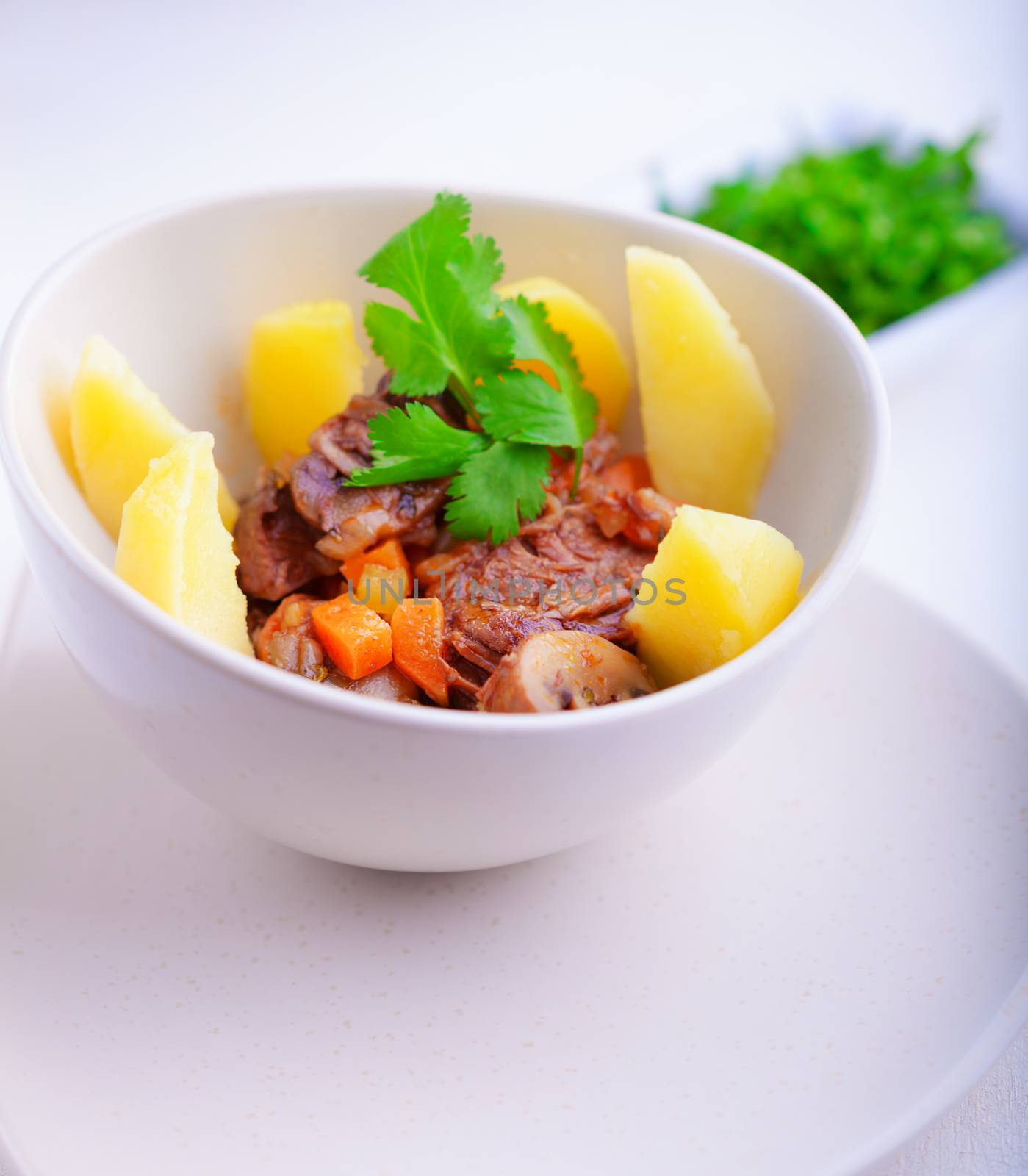 Beef stew being in a slow cooker, garnished with potatoes and carrots.