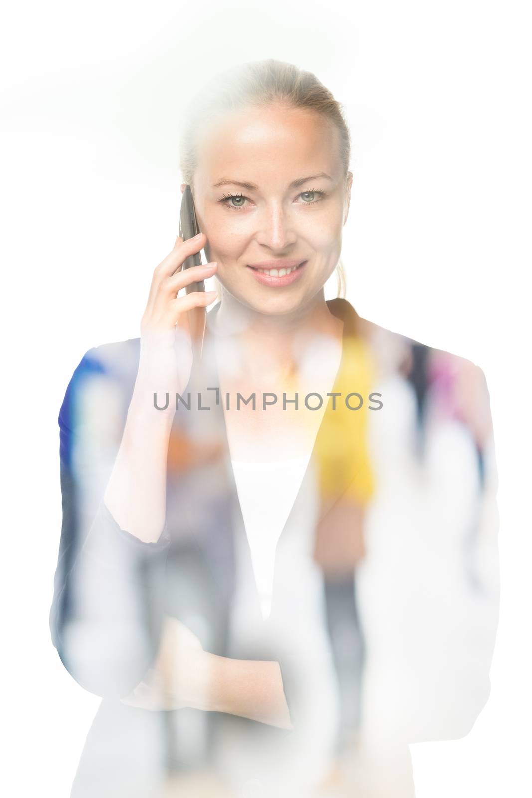 Beautiful young caucasian woman in business attire talking on smart phone on white background. Double exposure with abstract blur of business people overlay.