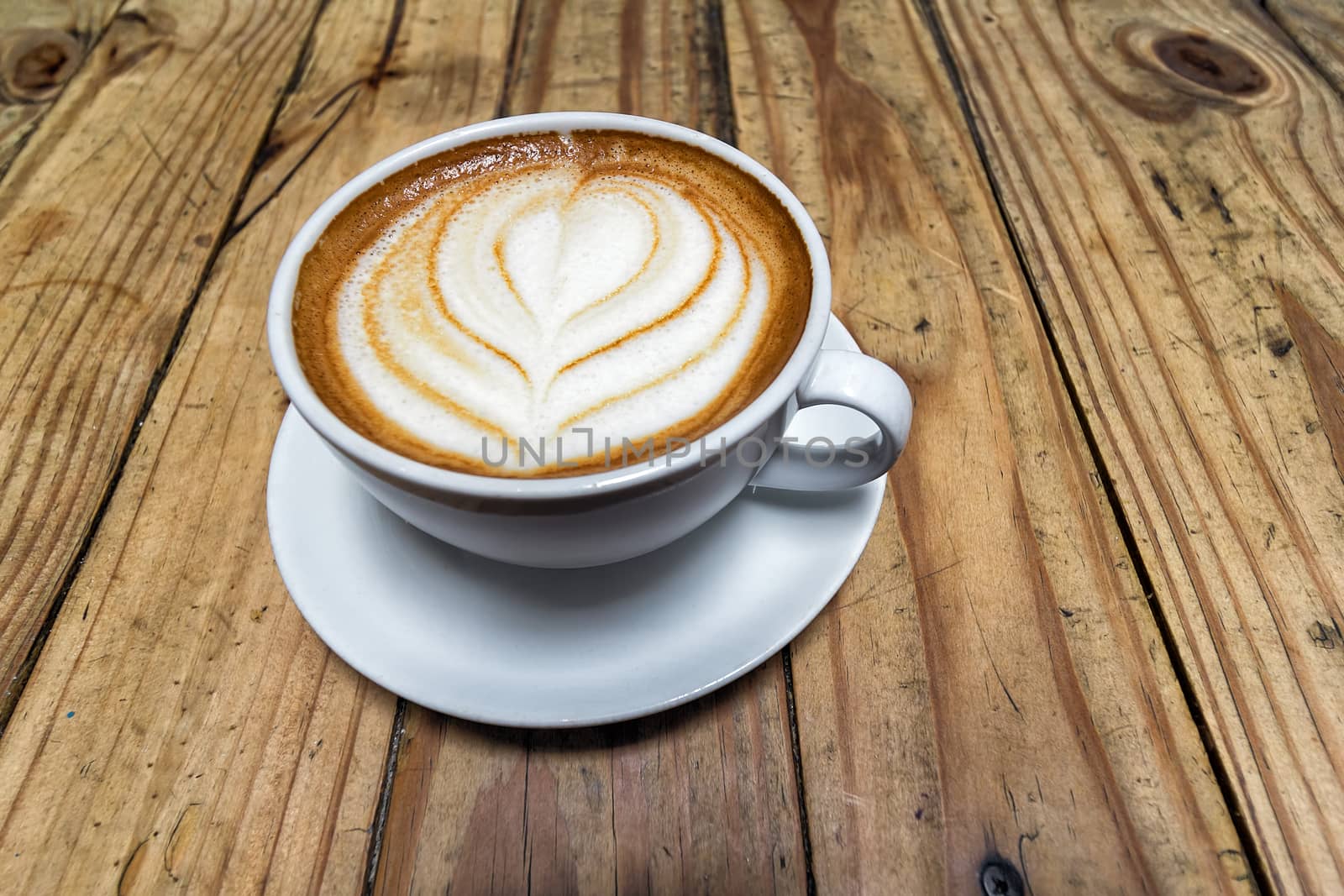 Cup of Foamy Latte on Grunge Wood Table Background