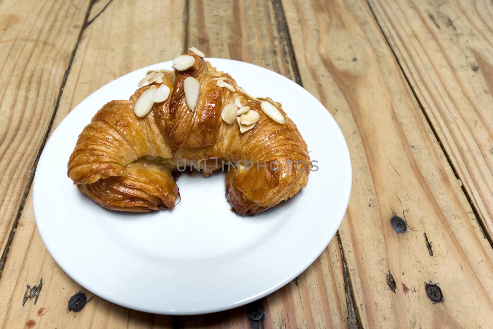Almond Croissant Pastry on a White Plate on Wood Table