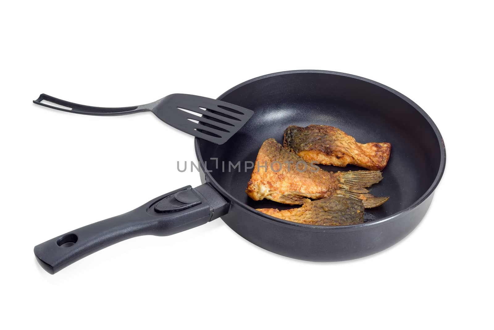 Fried tail portion and other slices of carp on an aluminium cast frying pan with ceramic non-stick coating and plastic spatula on a light background
