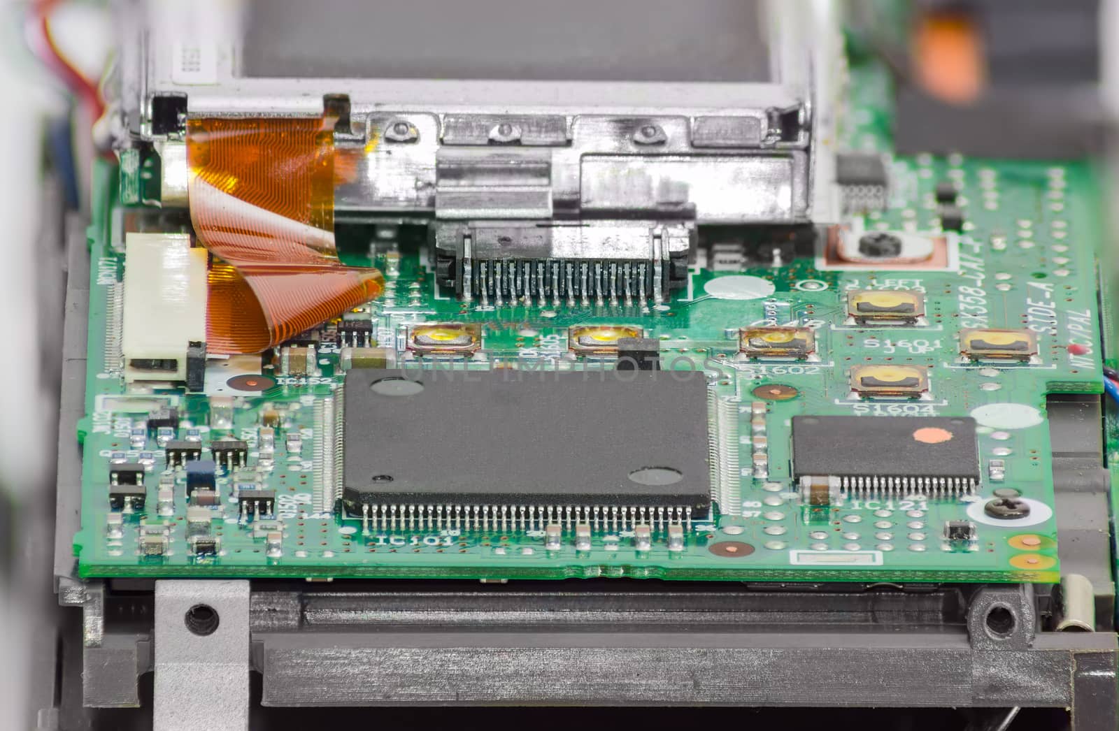 Fragment of electronic device with chips and other electronic components in foreground closeup
