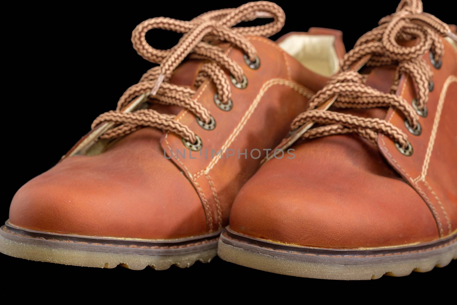 Toes of new leather brown mens shoe  with a shoelaces and eyelets on a dark background closeup
