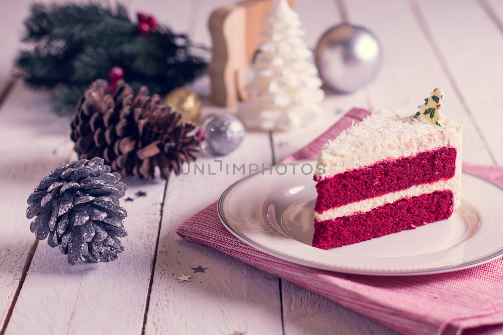 Christmas cake on plate on red fabric on wood background and decorations.