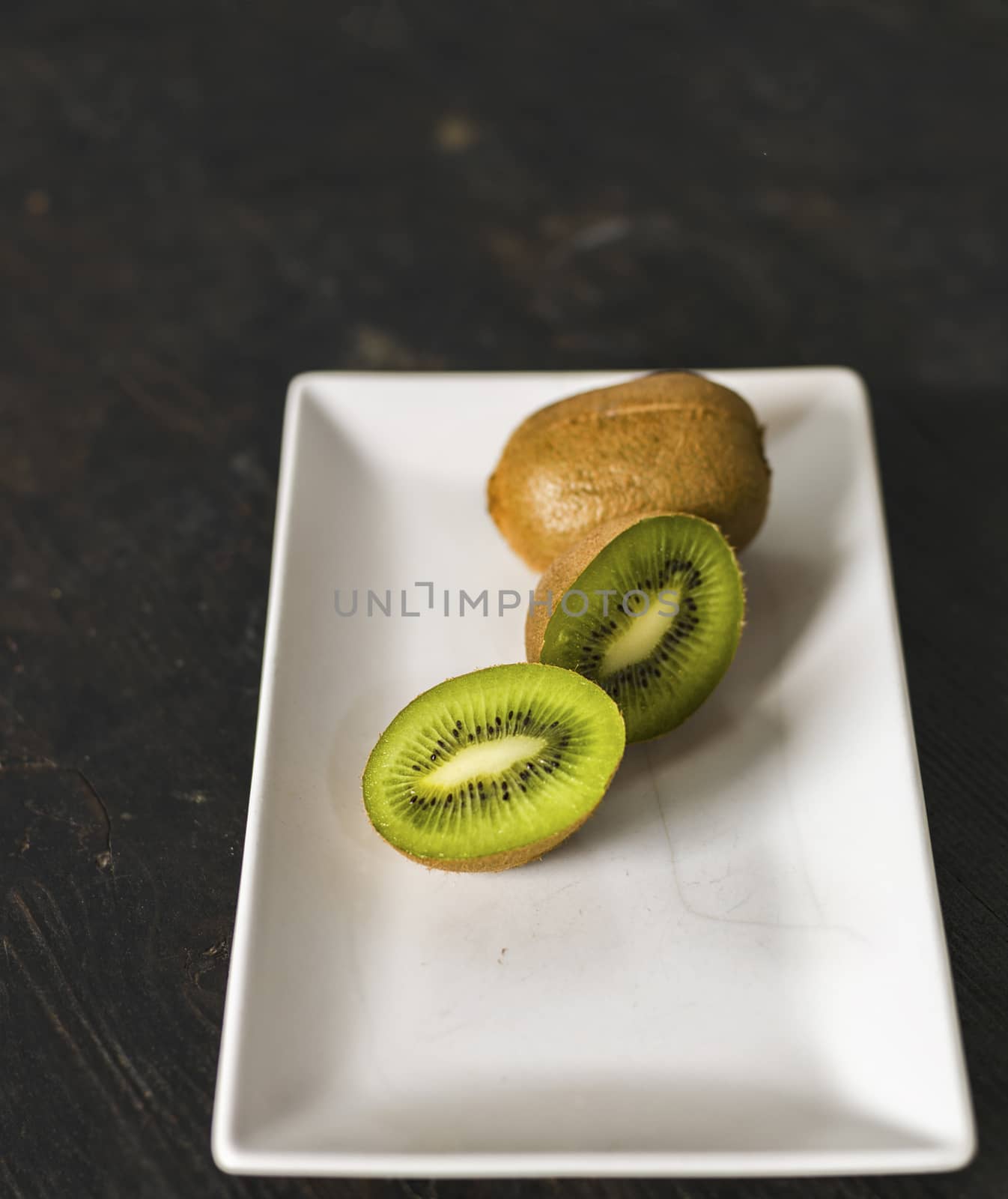 Kiwi fruit over a dark wooden table, shabby rustic mood.