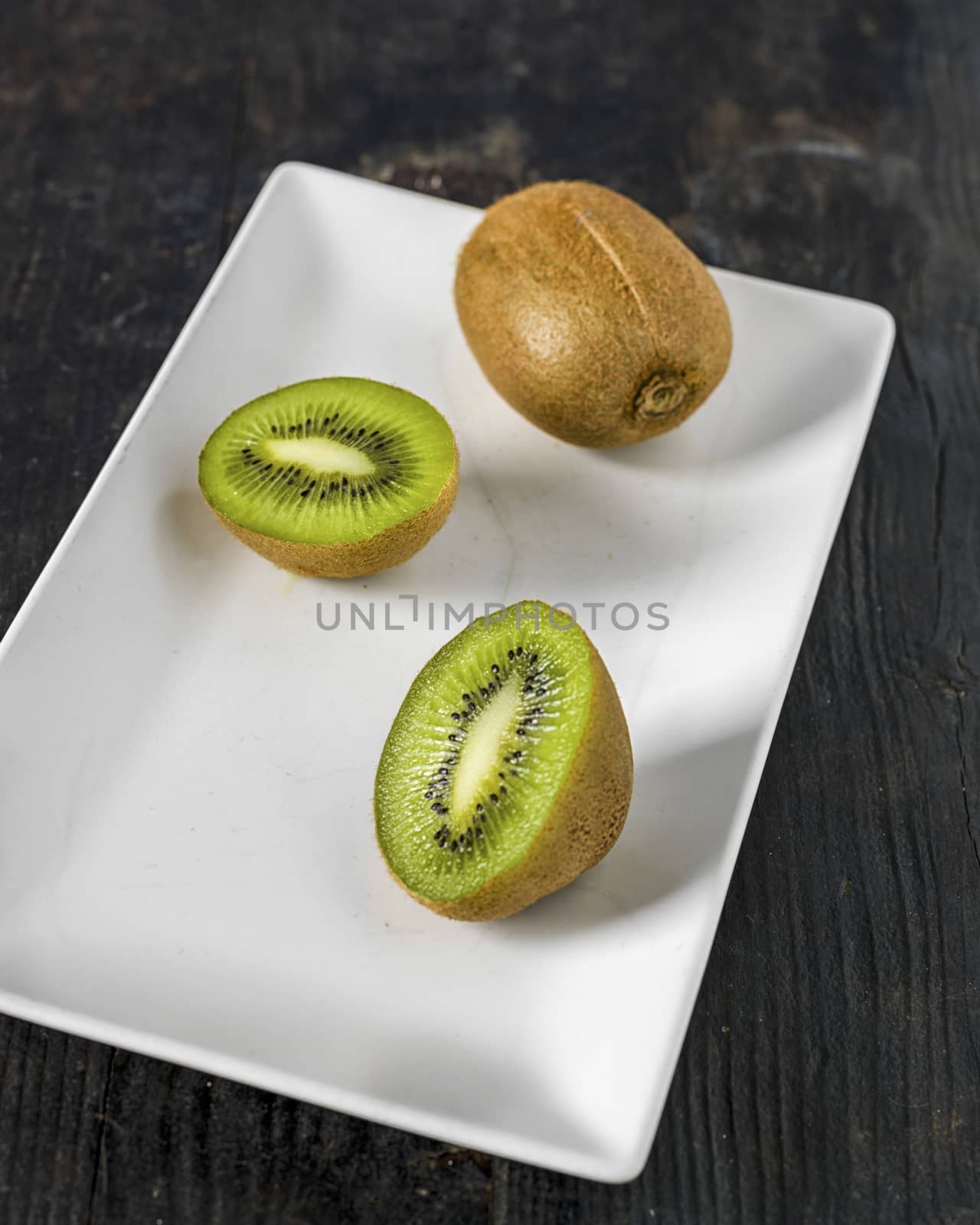 Kiwi fruit over a dark wooden table, shabby rustic mood.