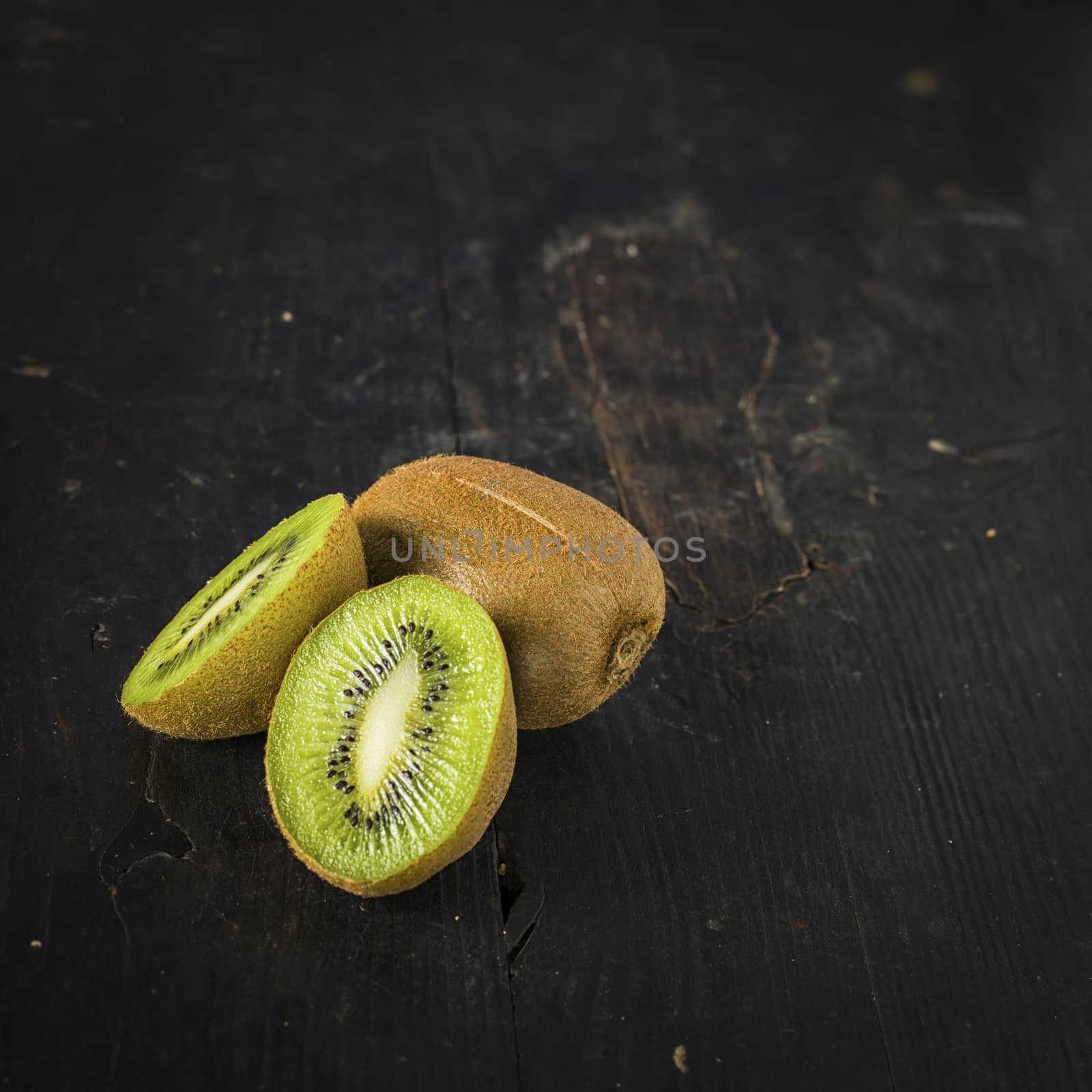 Kiwi fruit over a dark wooden table, shabby rustic mood.