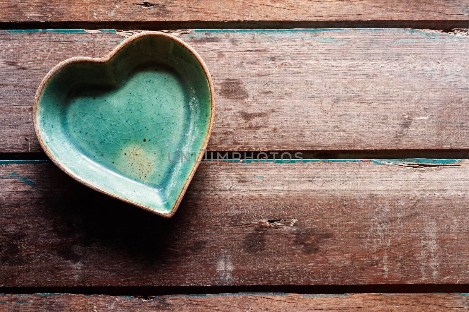Coffee cup saucer shaped heart on old wood floors.