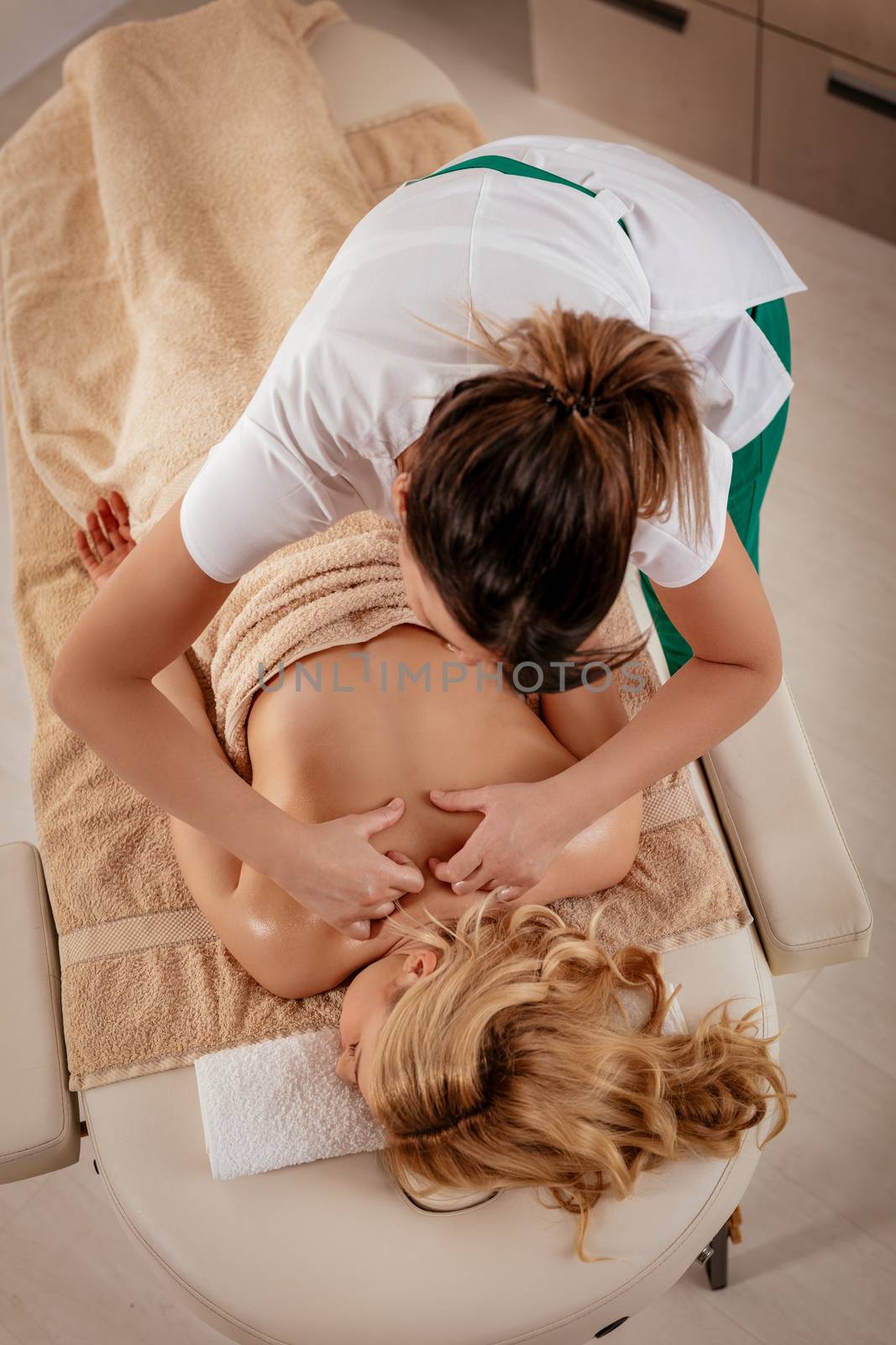 Young beautiful massage therapist giving a relax massage to a female client.