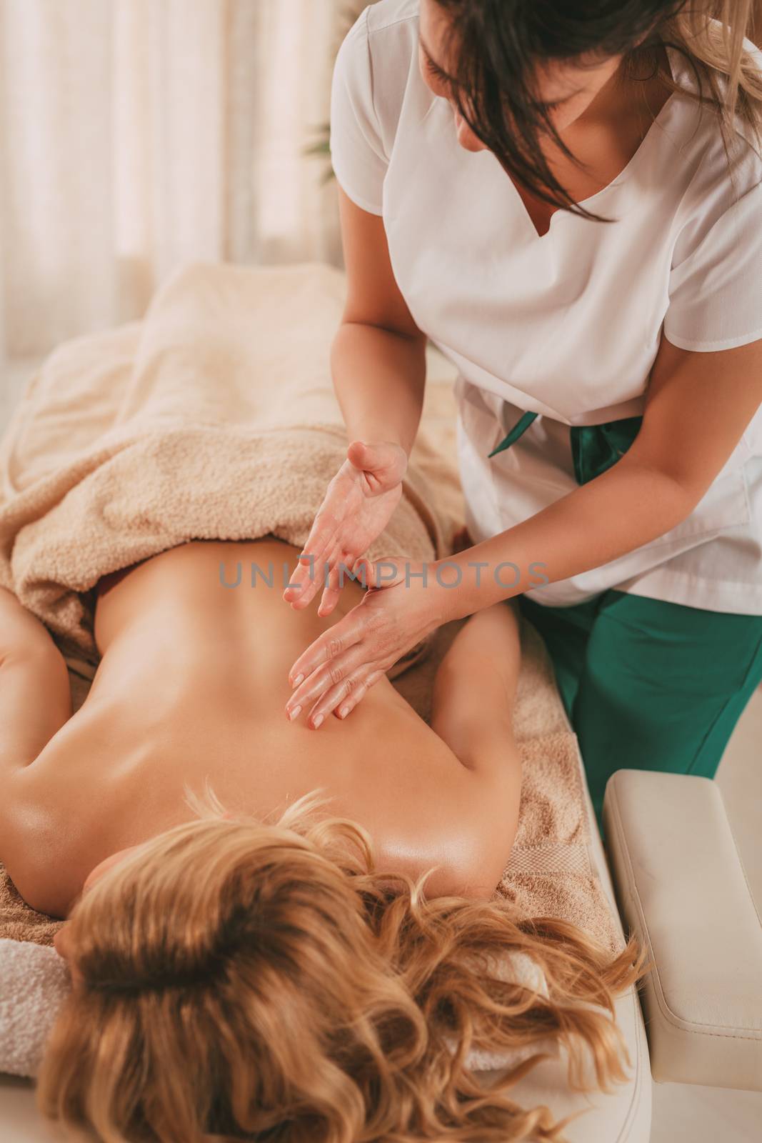 Young massage therapist giving a relax massage to a female client.