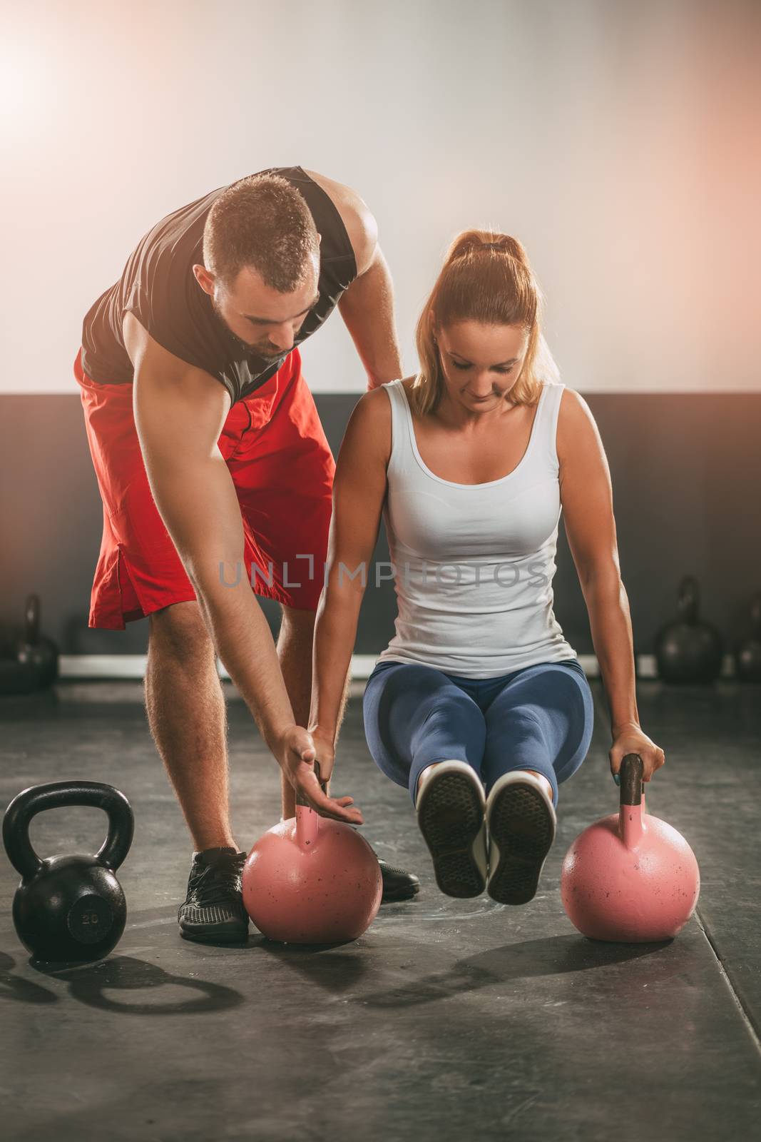 Young woman exercising at the gym with a personal trainer.