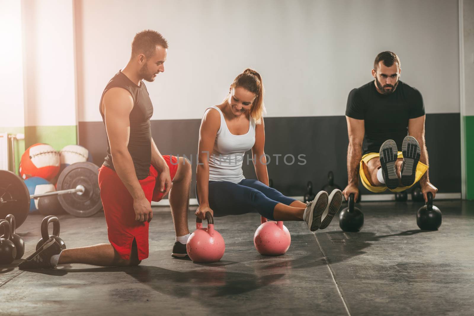 Young woman and man exercising at the gym with a personal trainer.
