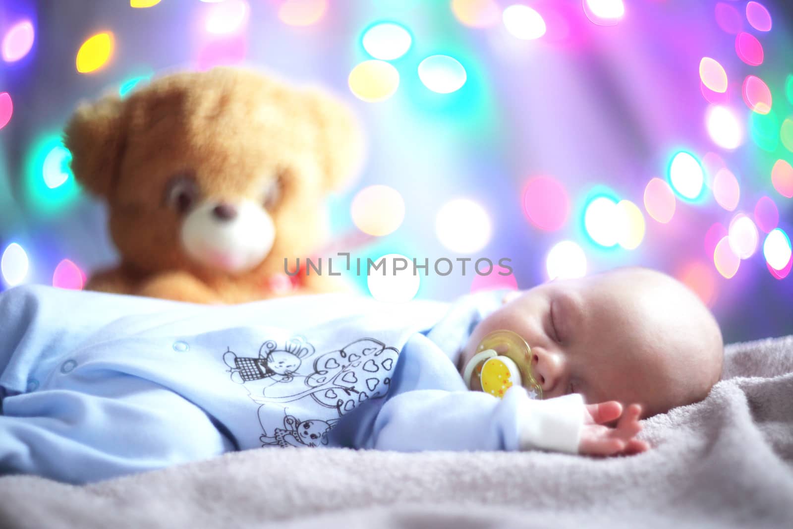 Newborn baby and teddy bear on light bokeh background