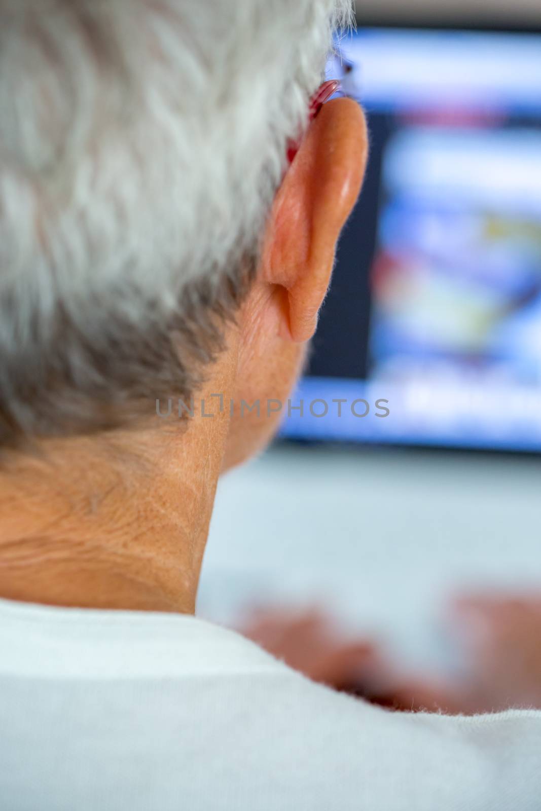 An old person with a pair of glasses in front of a laptop screen