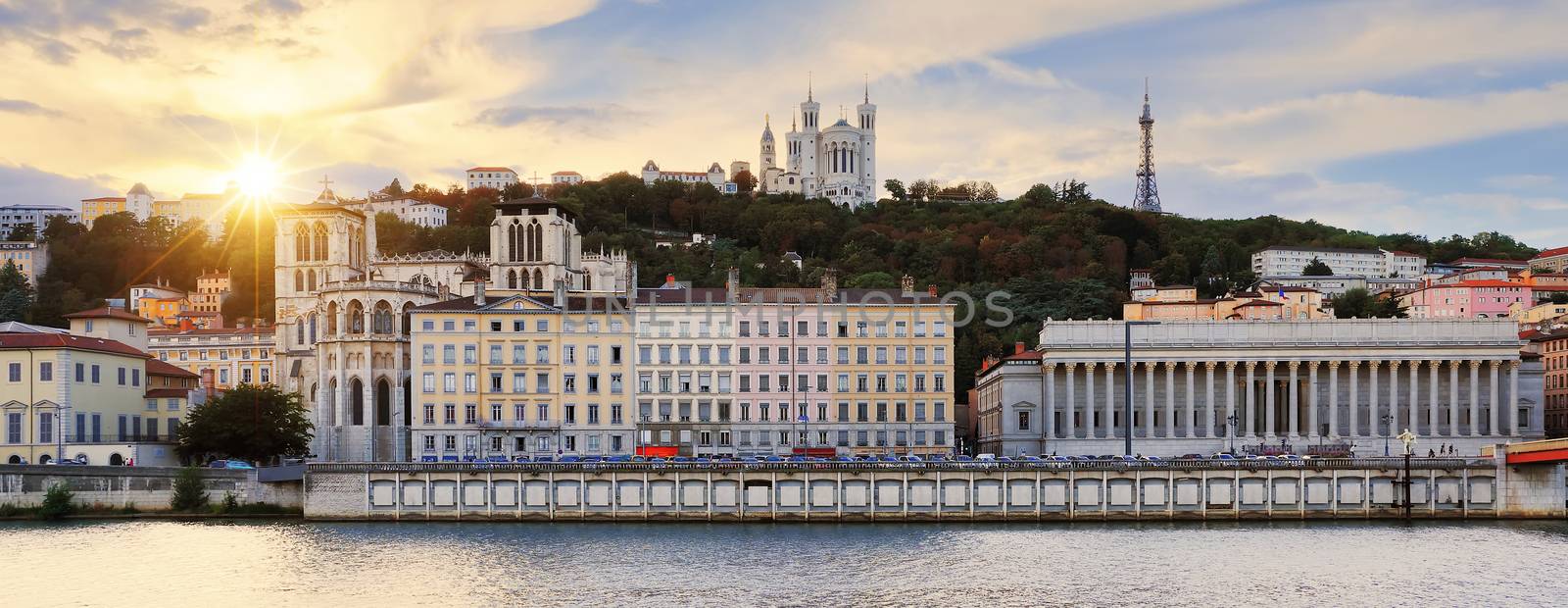 Colorful, cloudy sunset over Vieux Lyon and Fourviere Basilica seen from the riverbank of the Saone, Lyon.
