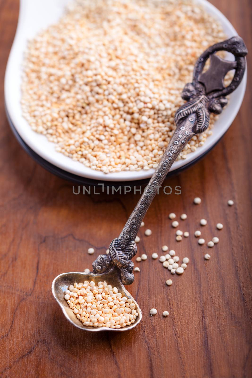 Raw quinoa wit a spoon on wooden table