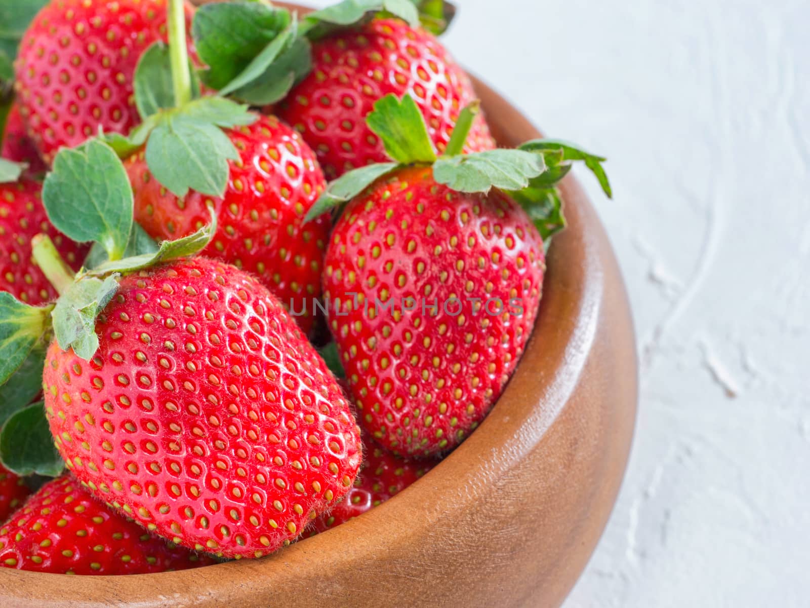 Fresh ripe strawberries in wooden bowl. Strawberry in bowl on oriental white background