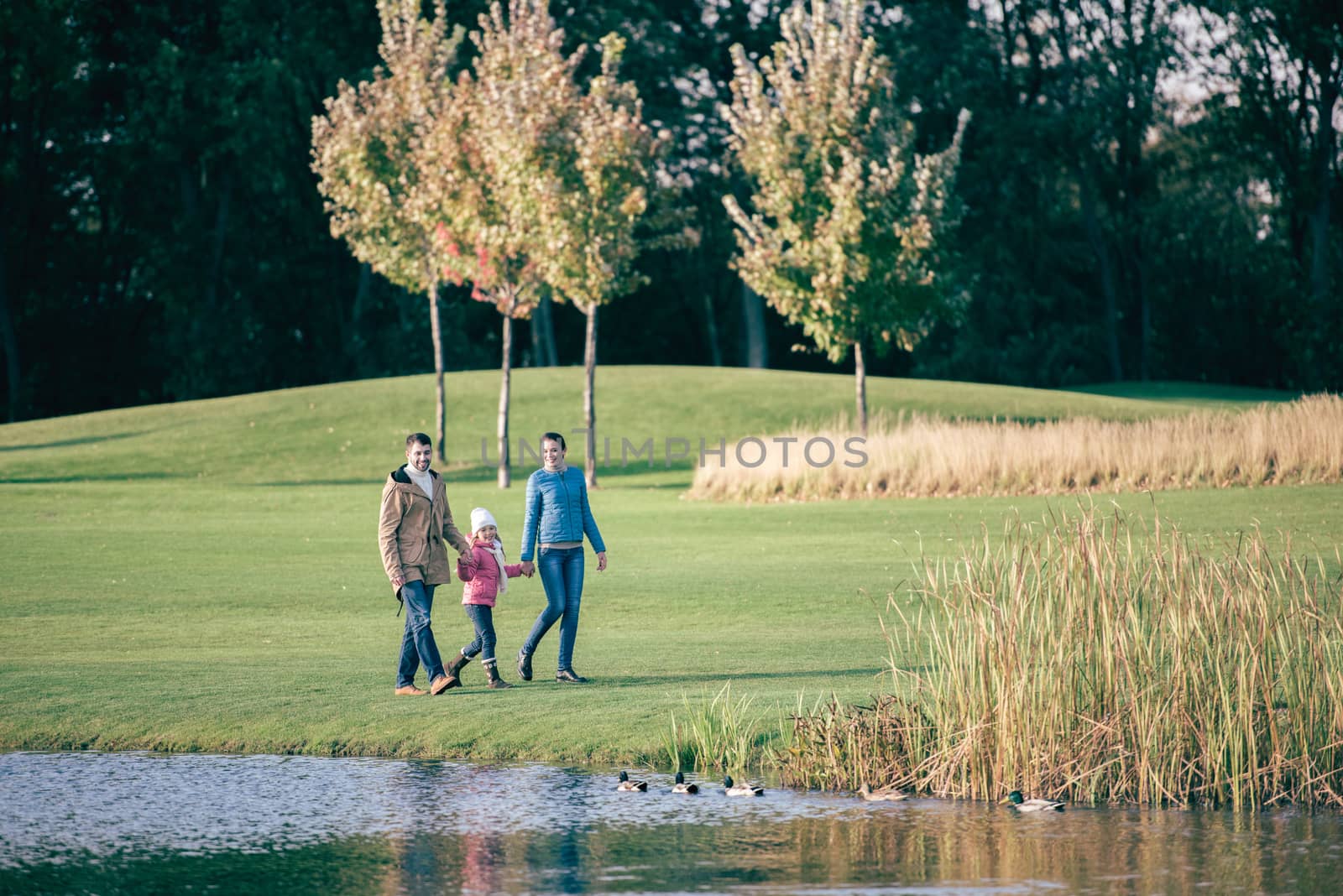 Happy family walking near lake by LightFieldStudios