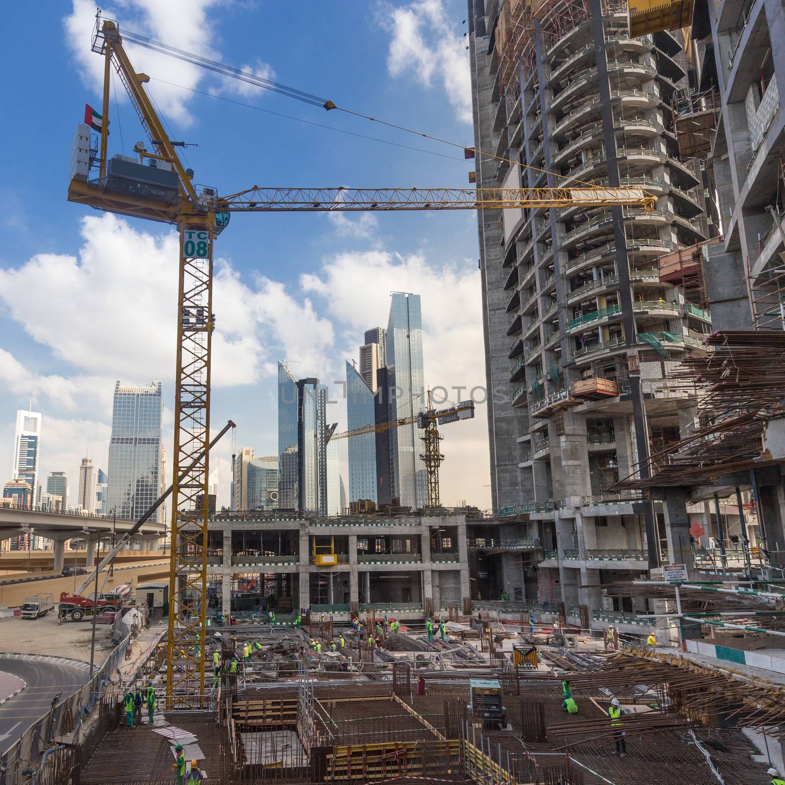 Laborers working on modern constraction site works in Dubai. Fast urban development consept.