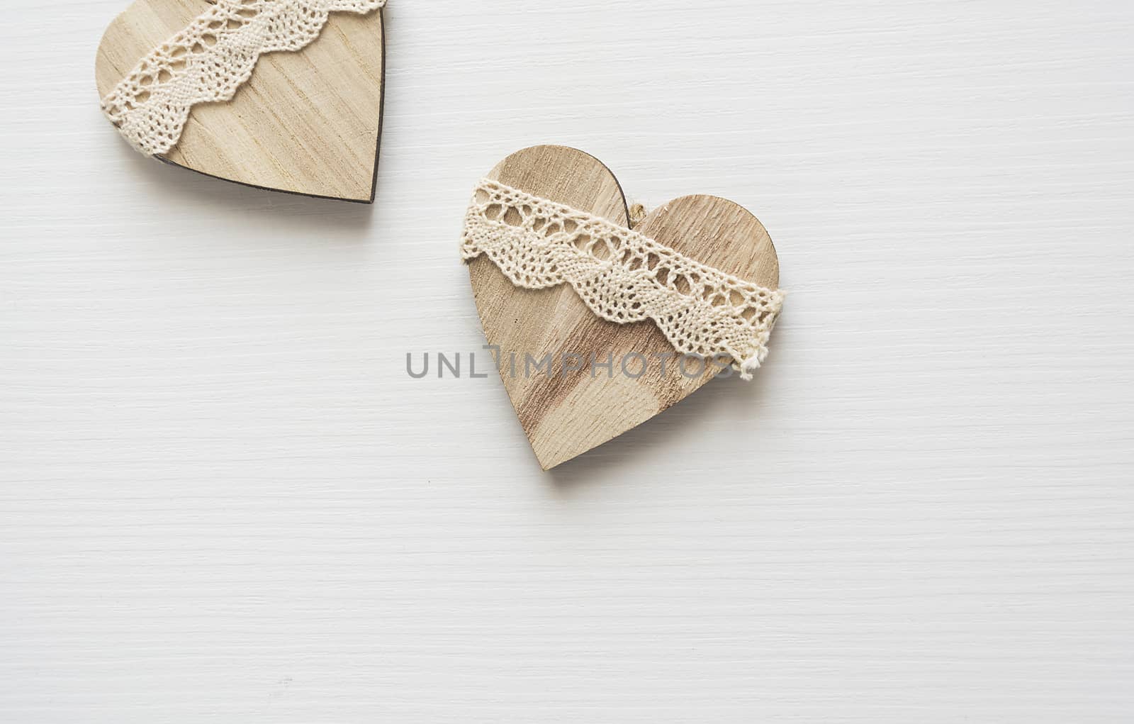 two wooden heart placed nicely on a white wood background