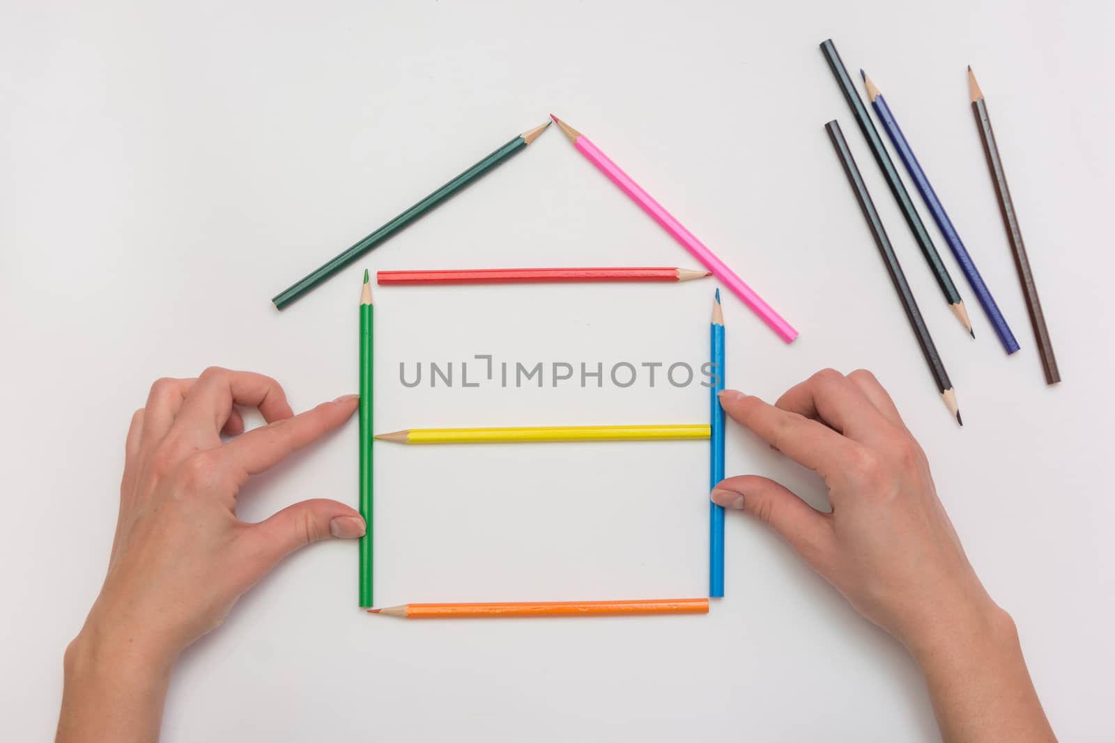 closeup Hands build a house on a piece of paper from the crayons, erecting walls by Madhourse