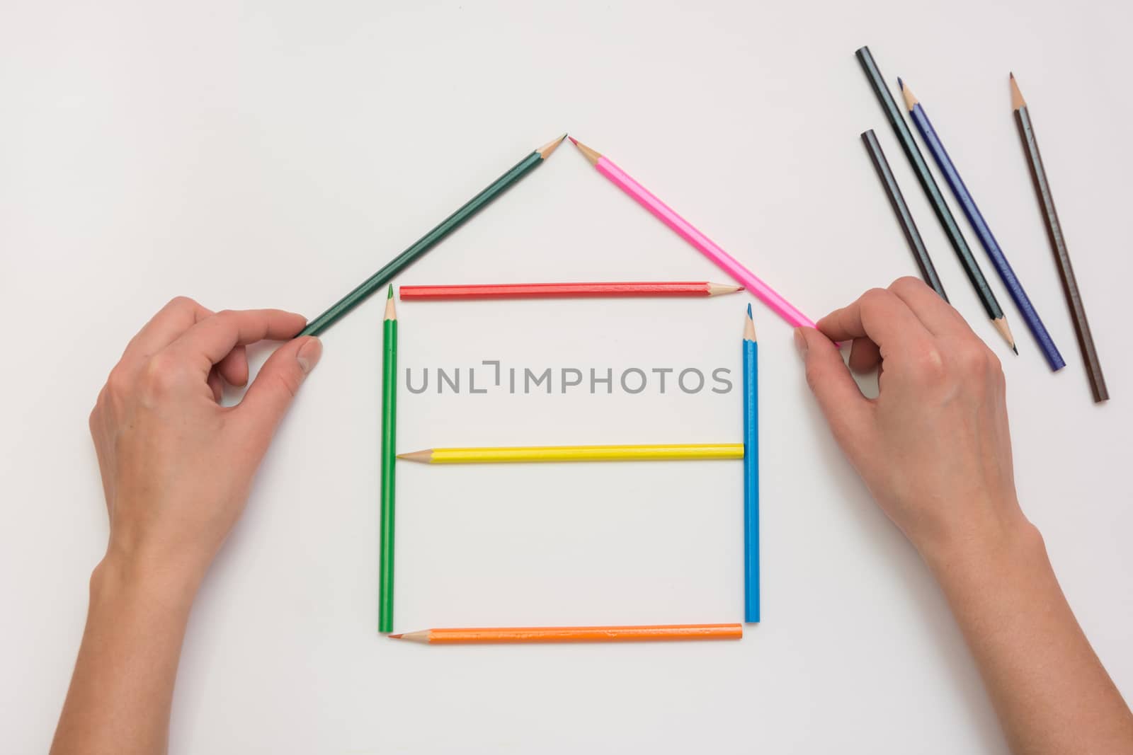 Hands close-up build a house on a piece of paper from the crayons