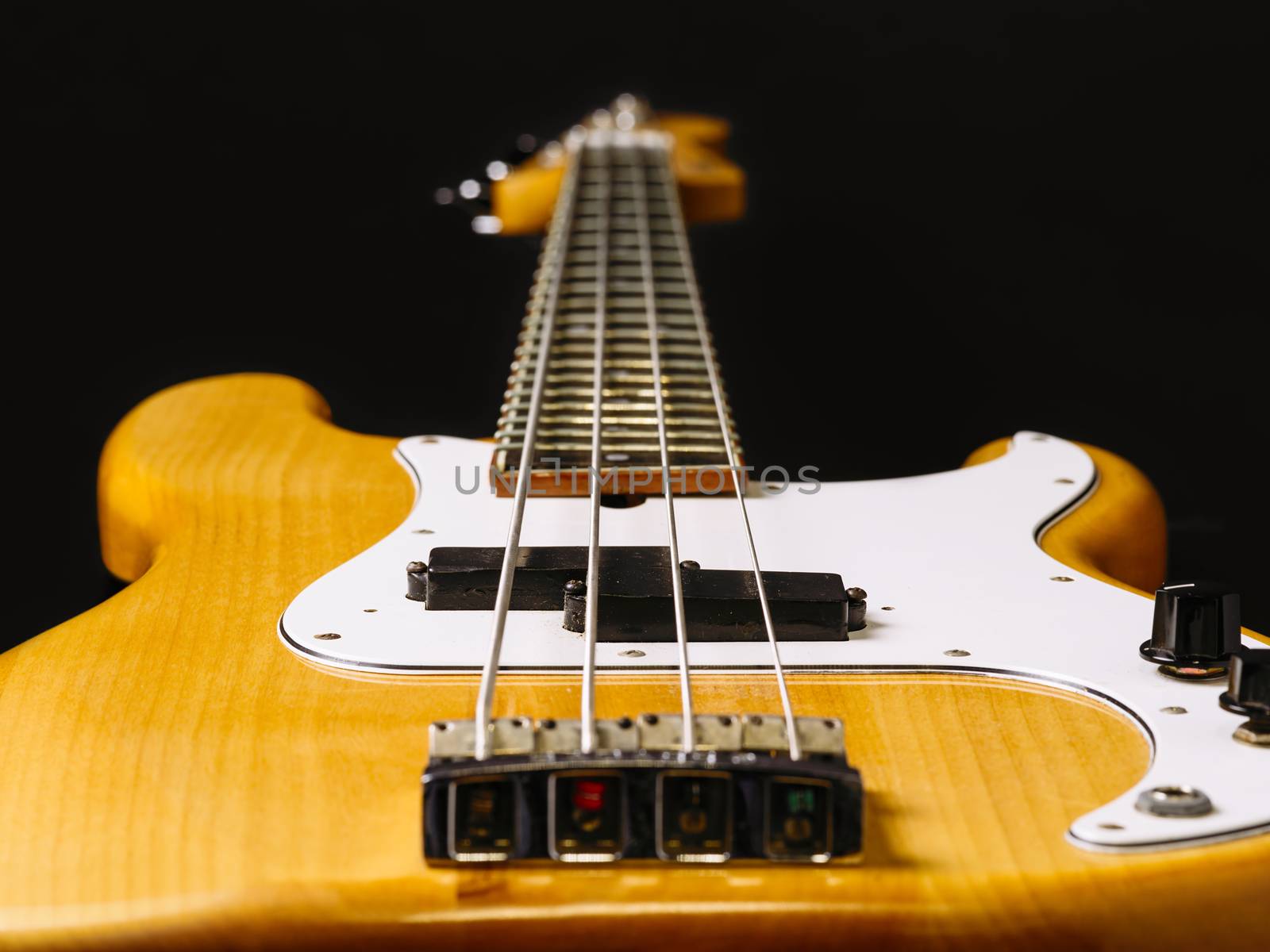 Photo of a electric bass guitar showing perspective from bottom to the headstock. Focus across middle.