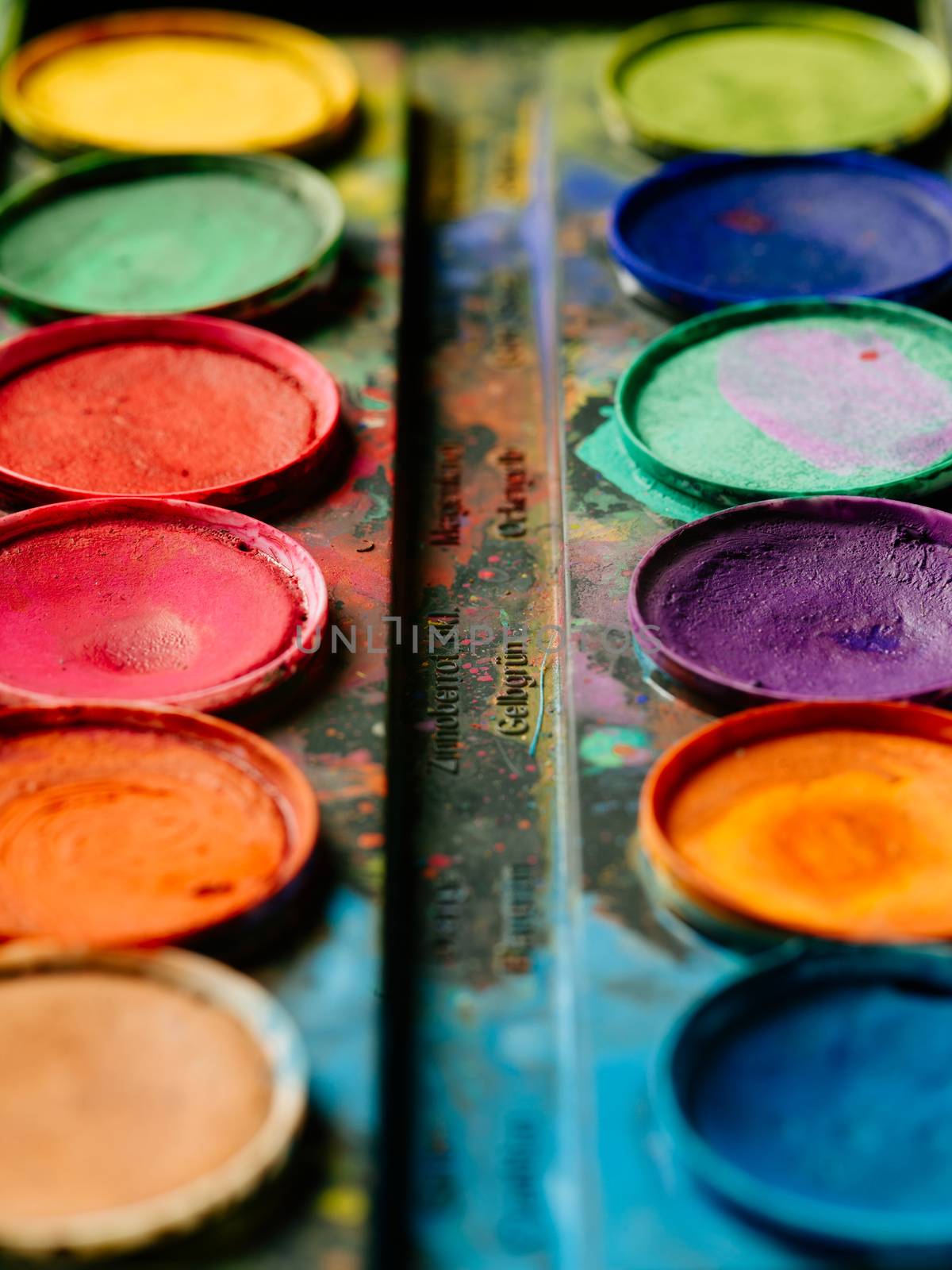 Photo of a palette of watercolor paints on a well-used tray.