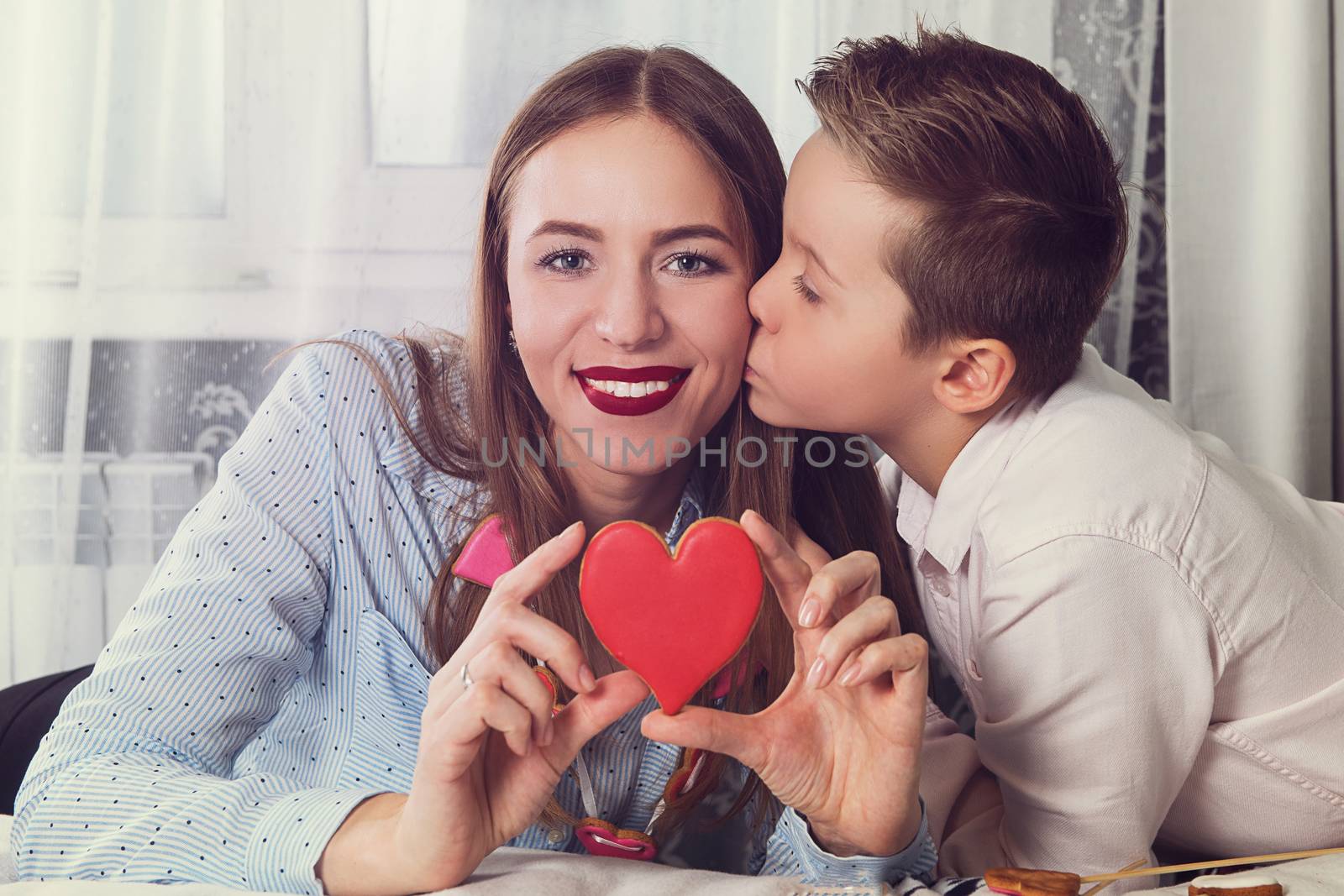 Happy Valentines Day or Mother day. Young boy spend time with her mum and celebrate with gingerbread heart cookies on a stick.