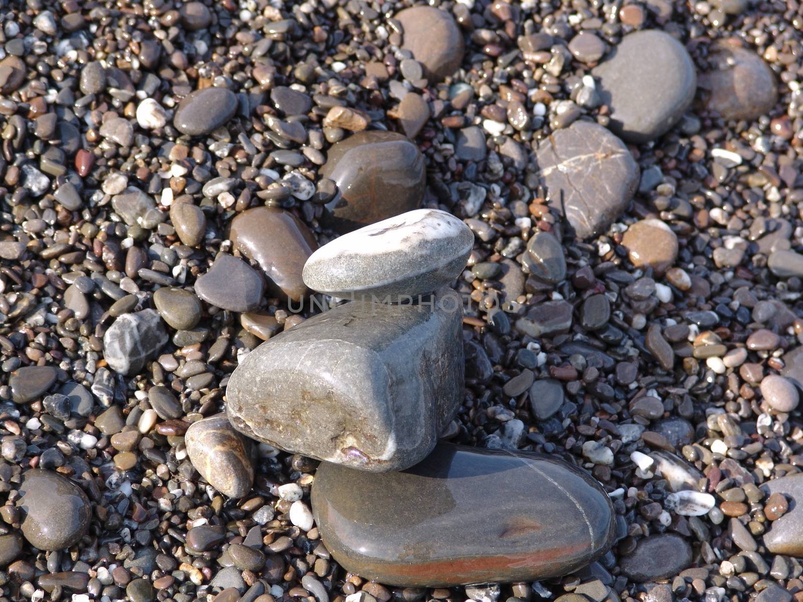 Stacked sea stones. Sea on the background. Contra light