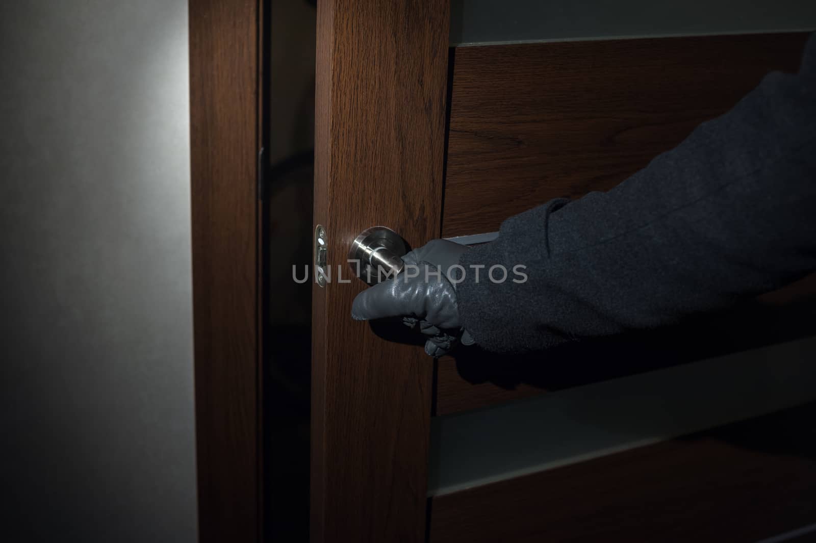 man wearing gloves opens the door at night by timonko