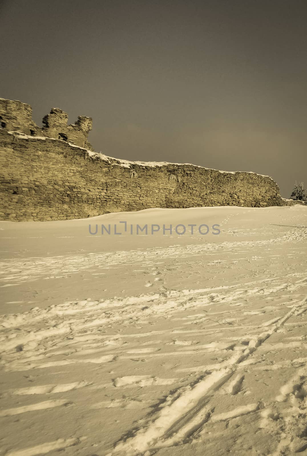 defensive wall of the old castle on snow background retro by Oleczka11