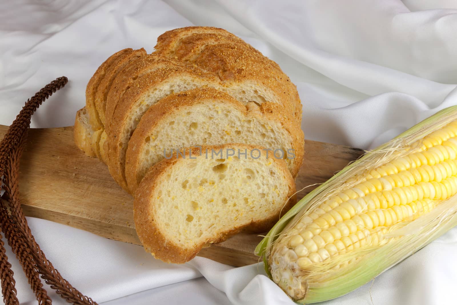 bread made from corn on the white fabric. Slices of corn bread laying on a chopping Board and Sweet corn cobs