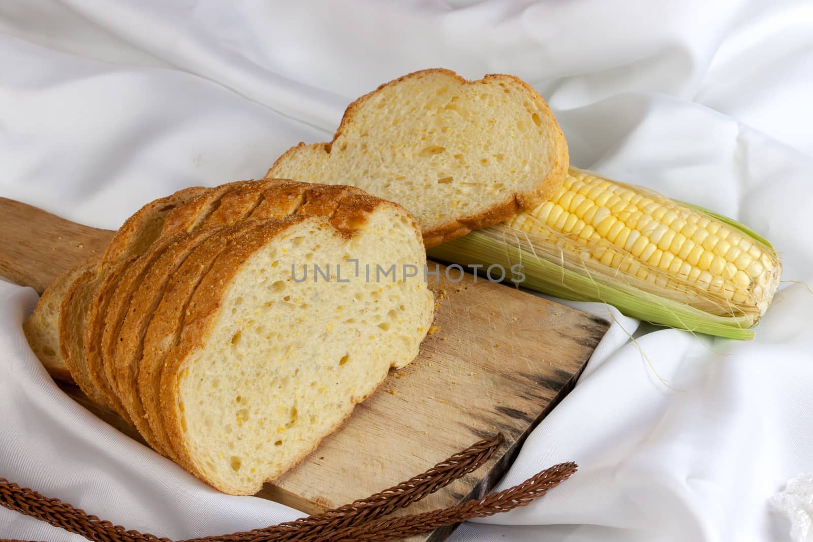 bread made from corn on the white fabric. Slices of corn bread laying on a chopping Board and Sweet corn cobs