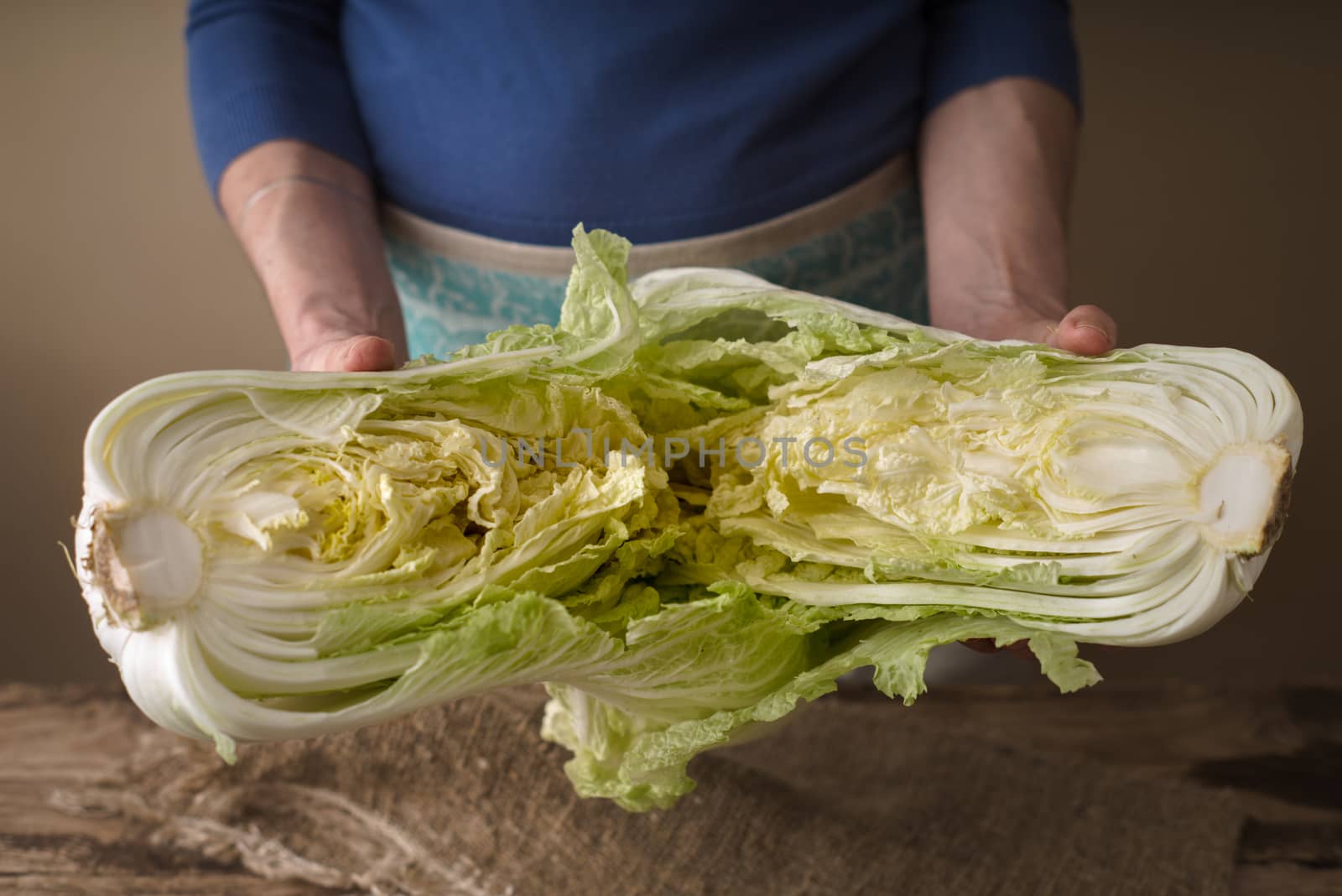 Woman shares the Chinese cabbage into two halves on the board by Deniskarpenkov