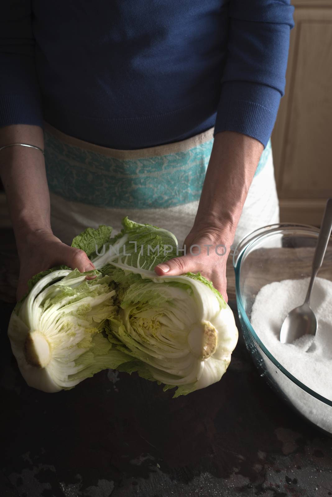 Woman Chinese cabbage divided into two halves for making kimchi vertical