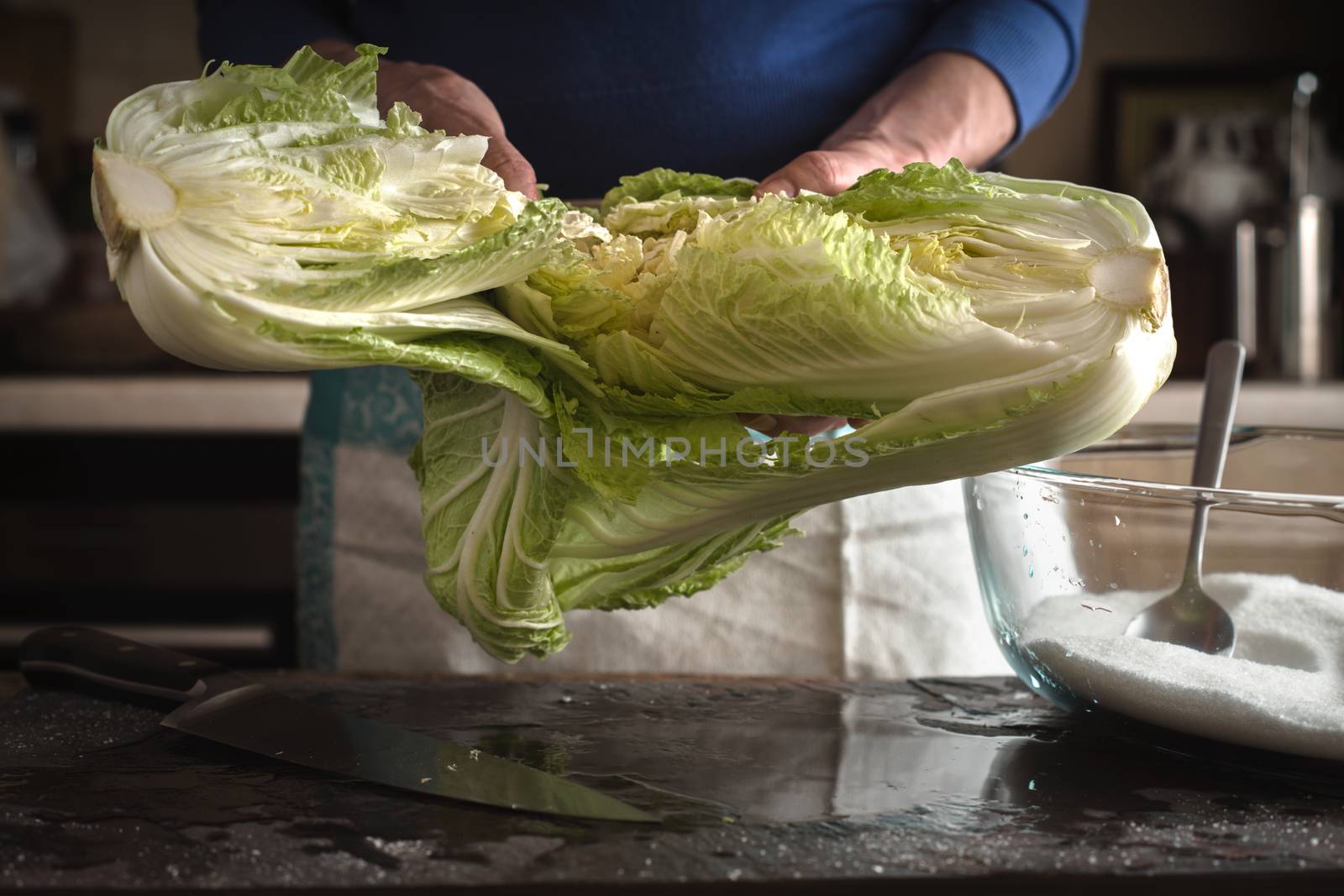 Woman salts for the preparation of Chinese cabbage kimchi on slate horizontal