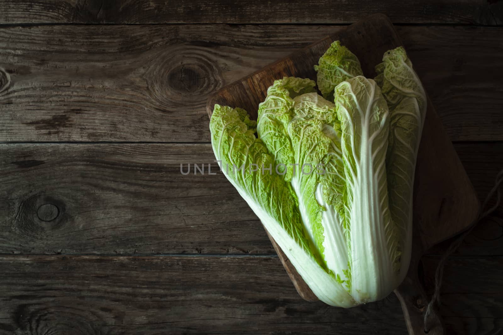 Chinese cabbage on a cutting board on old boards on right by Deniskarpenkov