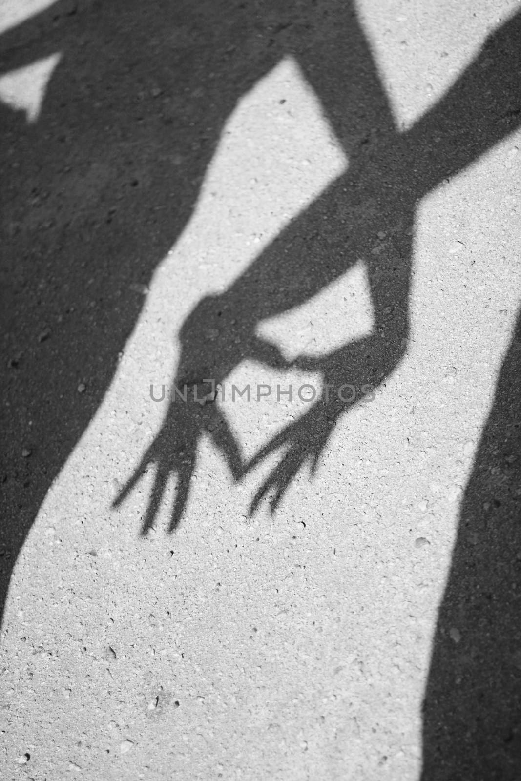 Two hands forming a heart shadow on the asphalt. Black and white photography