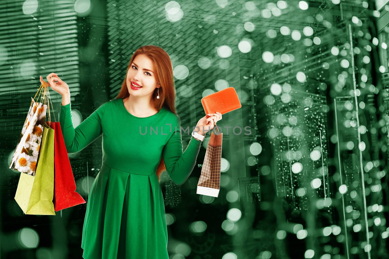 Beautiful happy girl posing with shopping bags against bokeh background. Christmas Lights in the windows of stores