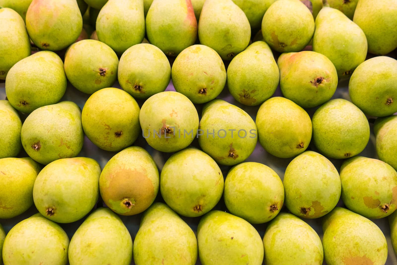 Background of a stacked ripe pears close up. Green pears pattern on sale at the market.