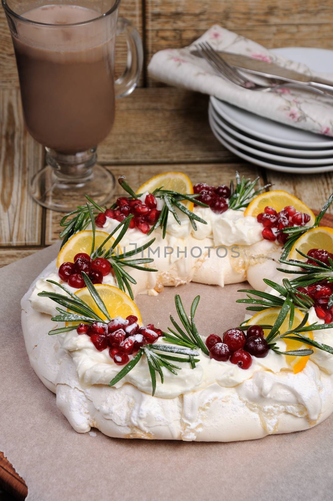 Pavlova cake in the form of a Christmas wreath of meringue with cream, pomegranate, cranberry, rosemary sprigs