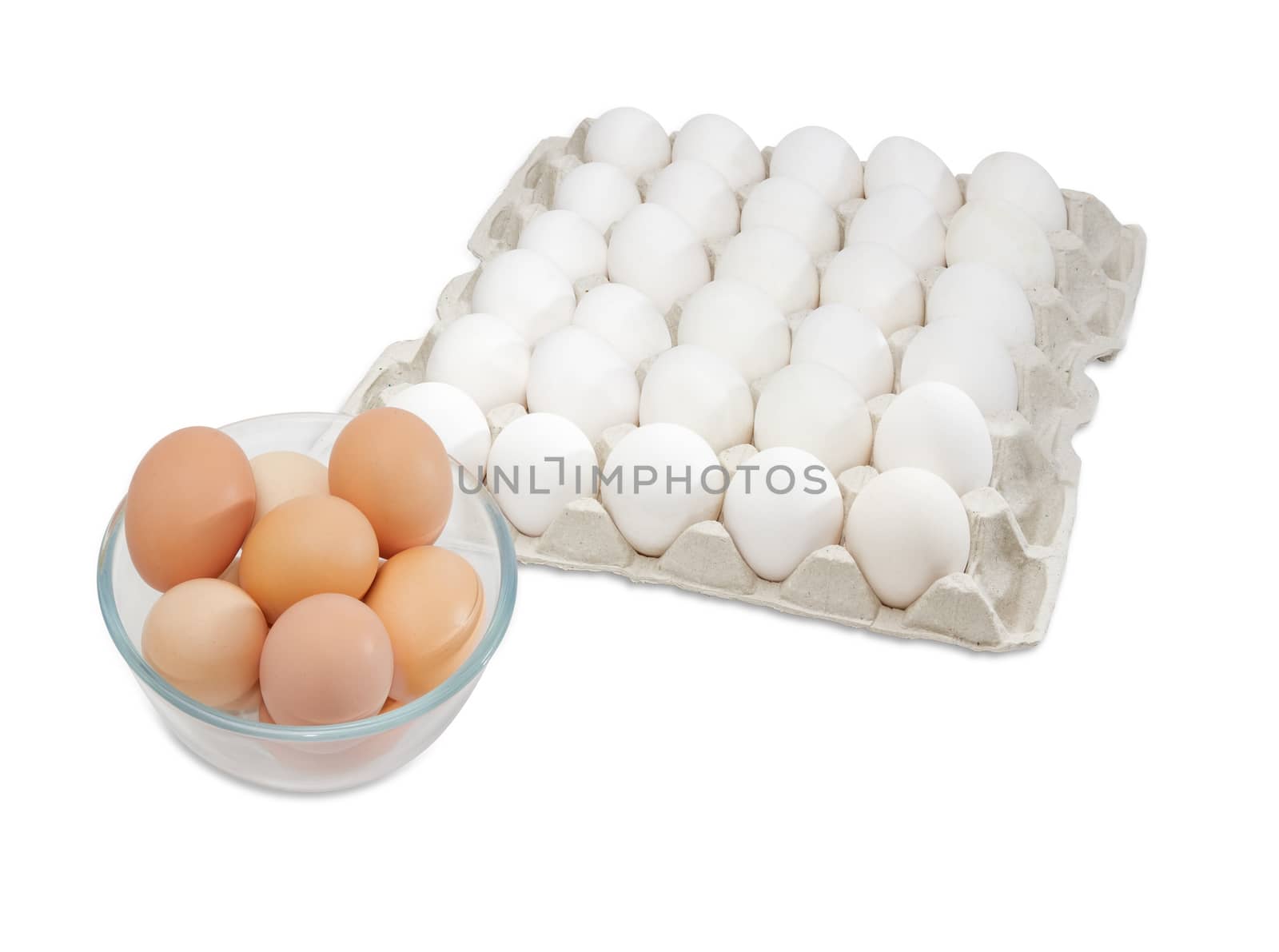 Fresh brown free-range eggs in a glass bowl and white chicken eggs in an egg tray from commercial factory farming on a light background
