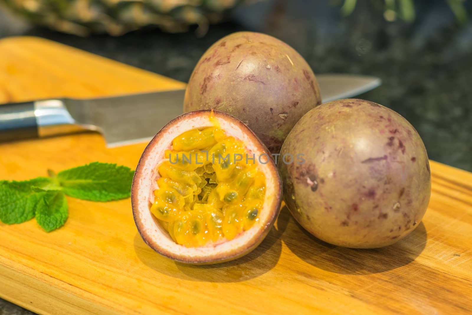 A couple of ripe passion fruit with a cut half in front
