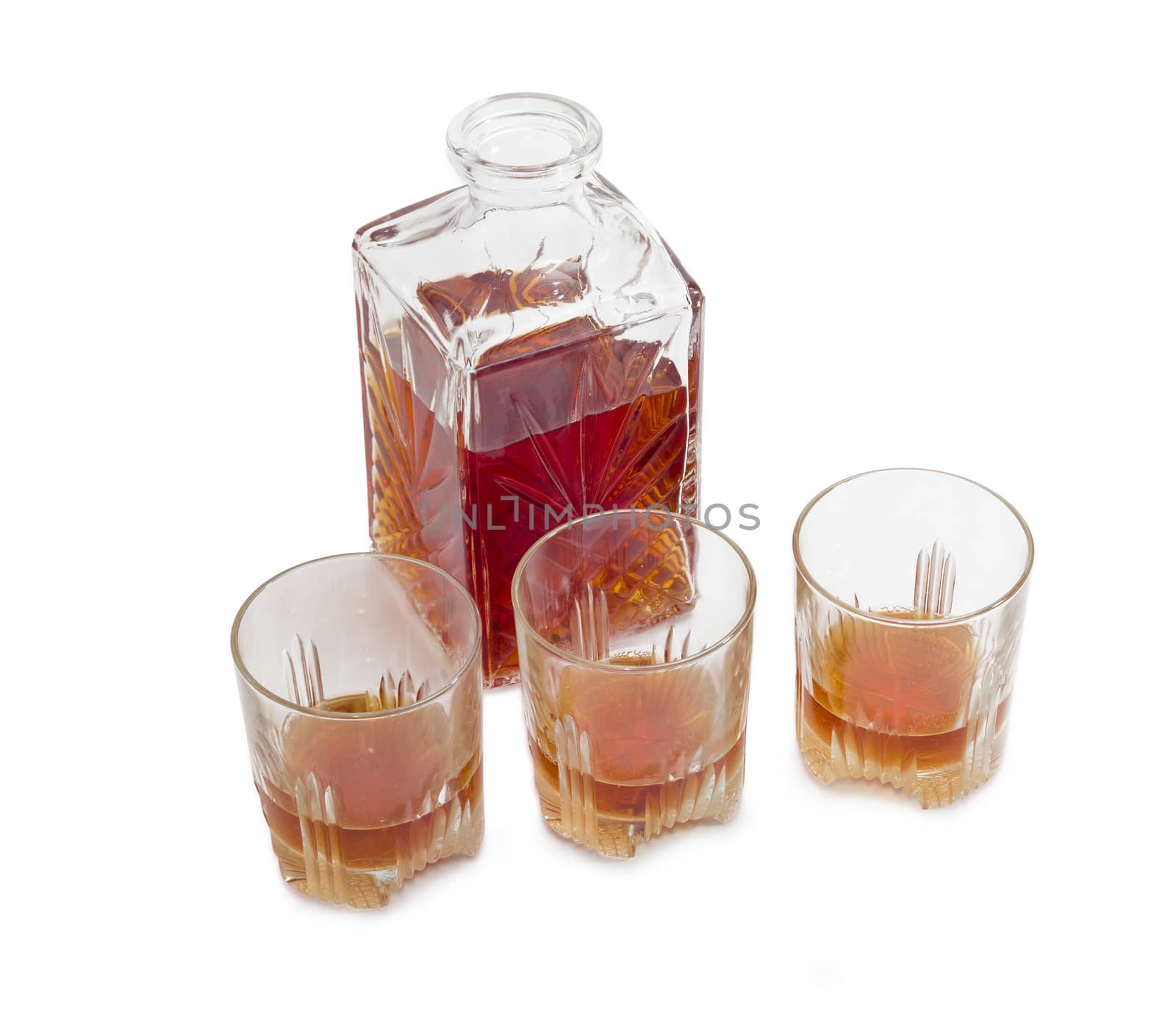 Opened decanter and three glasses with whiskey on a light background
