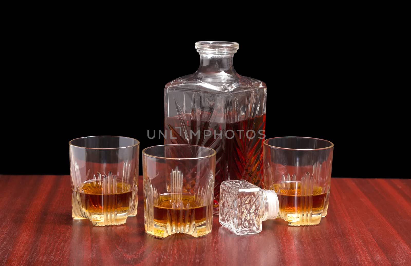 Decanter and three glasses with whiskey on a wooden table by anmbph