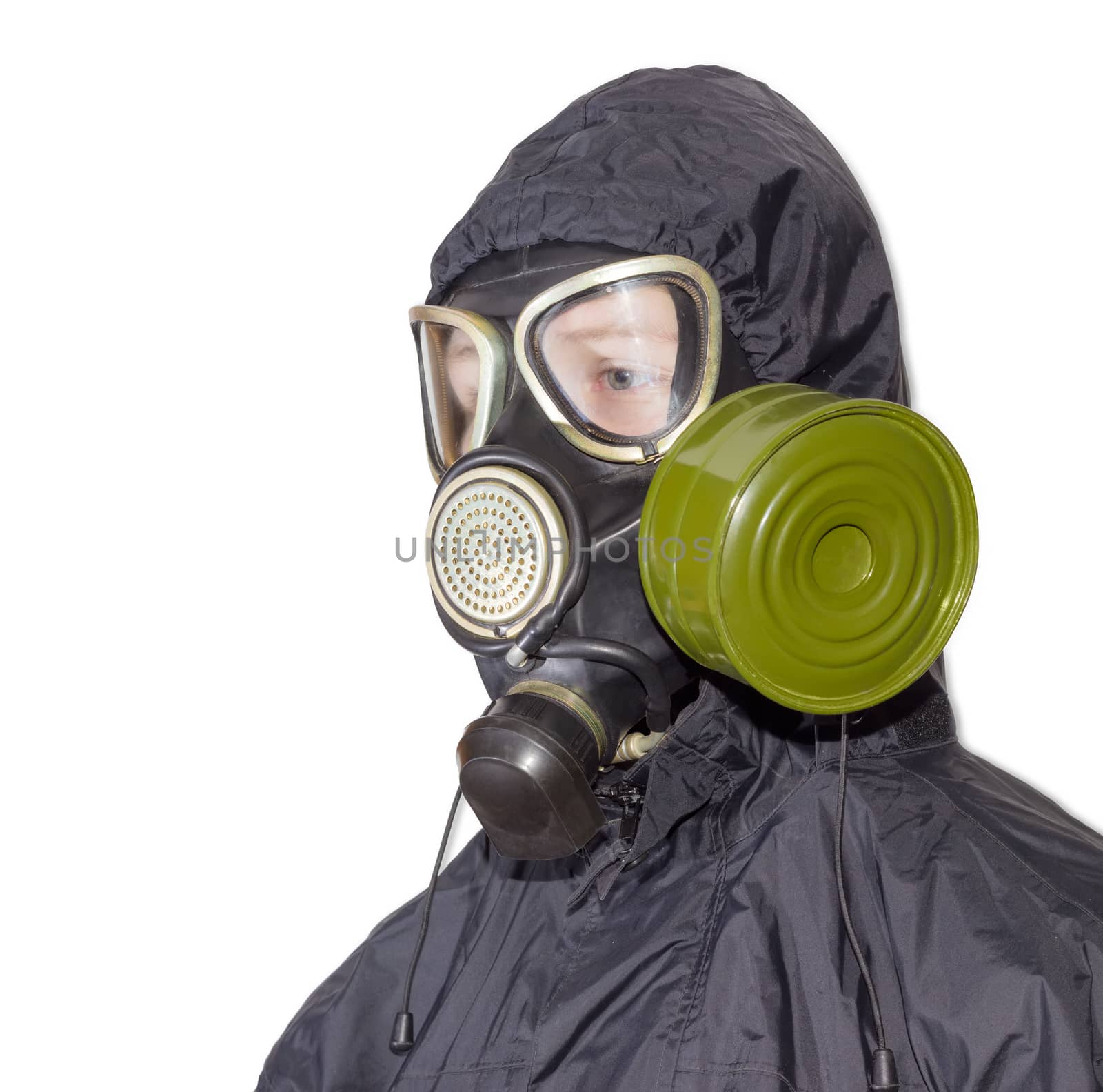Head and shoulders of a person in a rubber gas mask with filter mounted on side of the mask and drinking tube and in a black jacket with a hood on a light background
