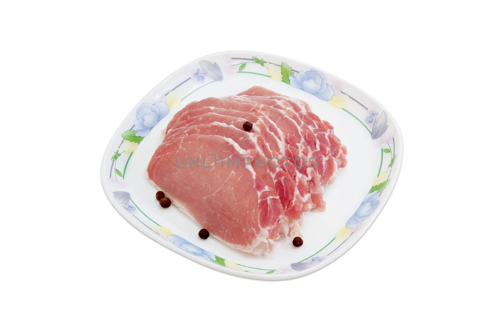 Sliced uncooked pork tenderloin and few peas allspiceon on a dish on a light background 
